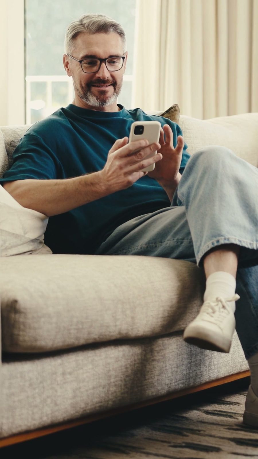 Empresário acompanhando o negócio pelo celular no sofá